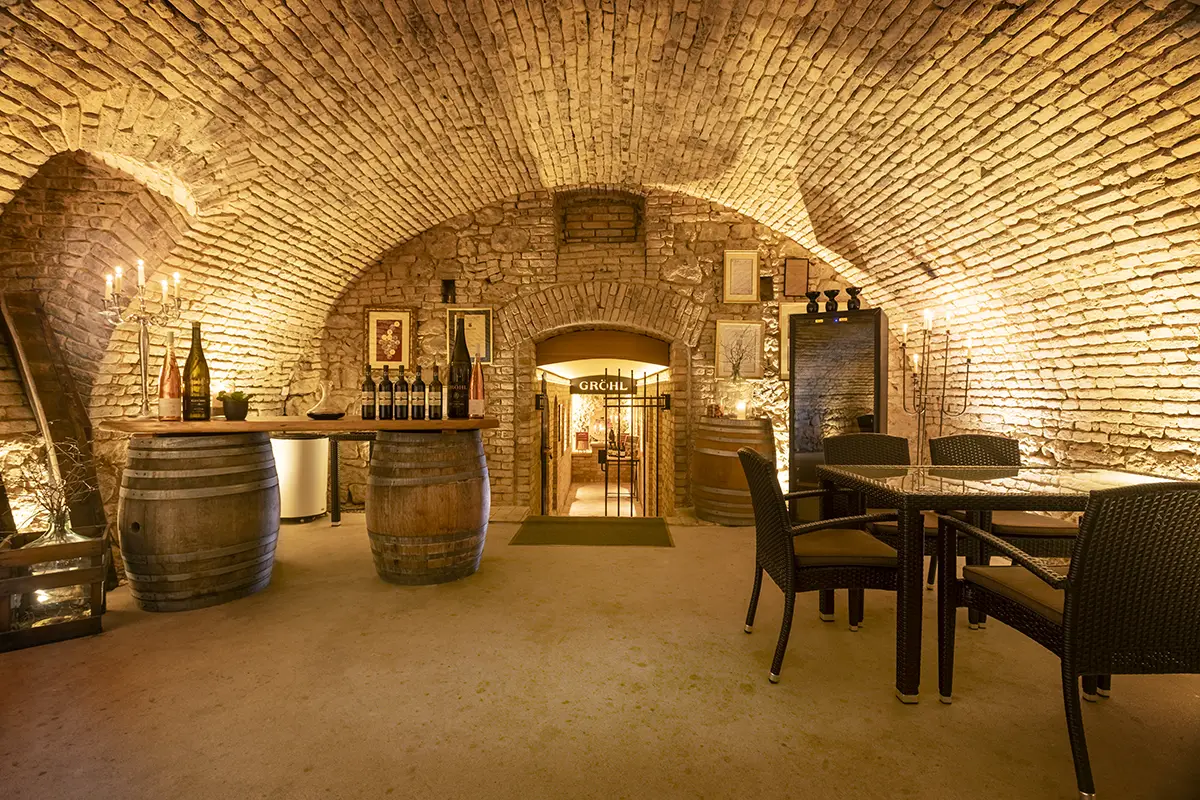 Die Schatzkammer der Vinothek im Weingut Gröhl – ein stilvoll beleuchteter Gewölbegang mit historischen Mauern, Auszeichnungen und Kerzen.